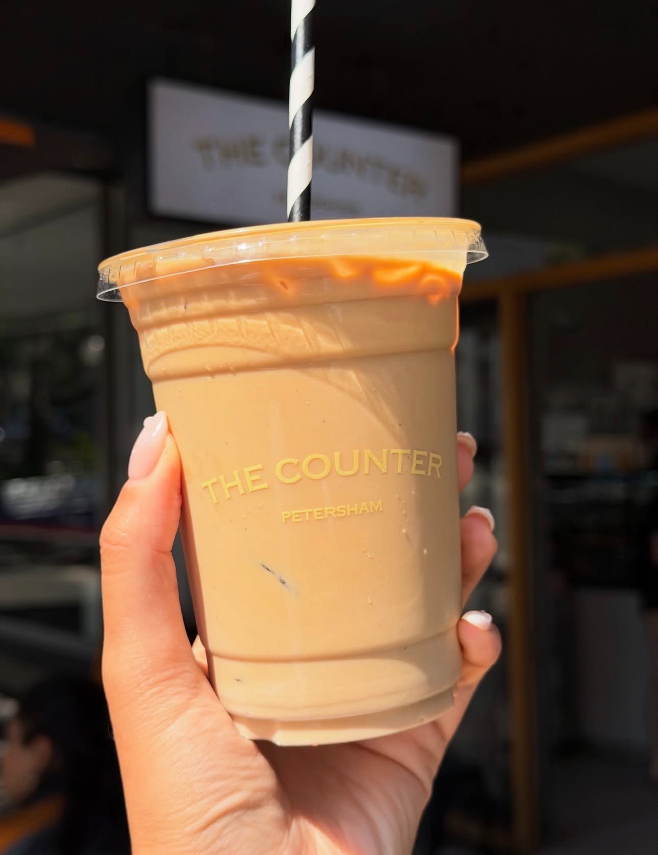 Iced coffee in a branded cup outside The Counter Petersham